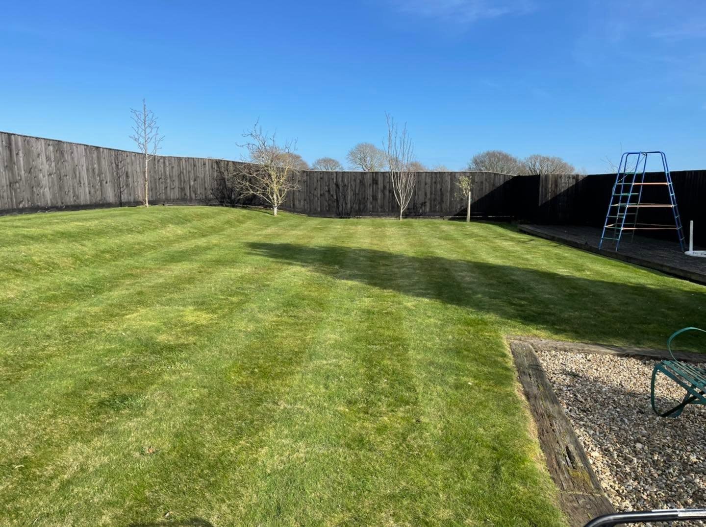 Long mown garden lawn enclosed by timber fencing
