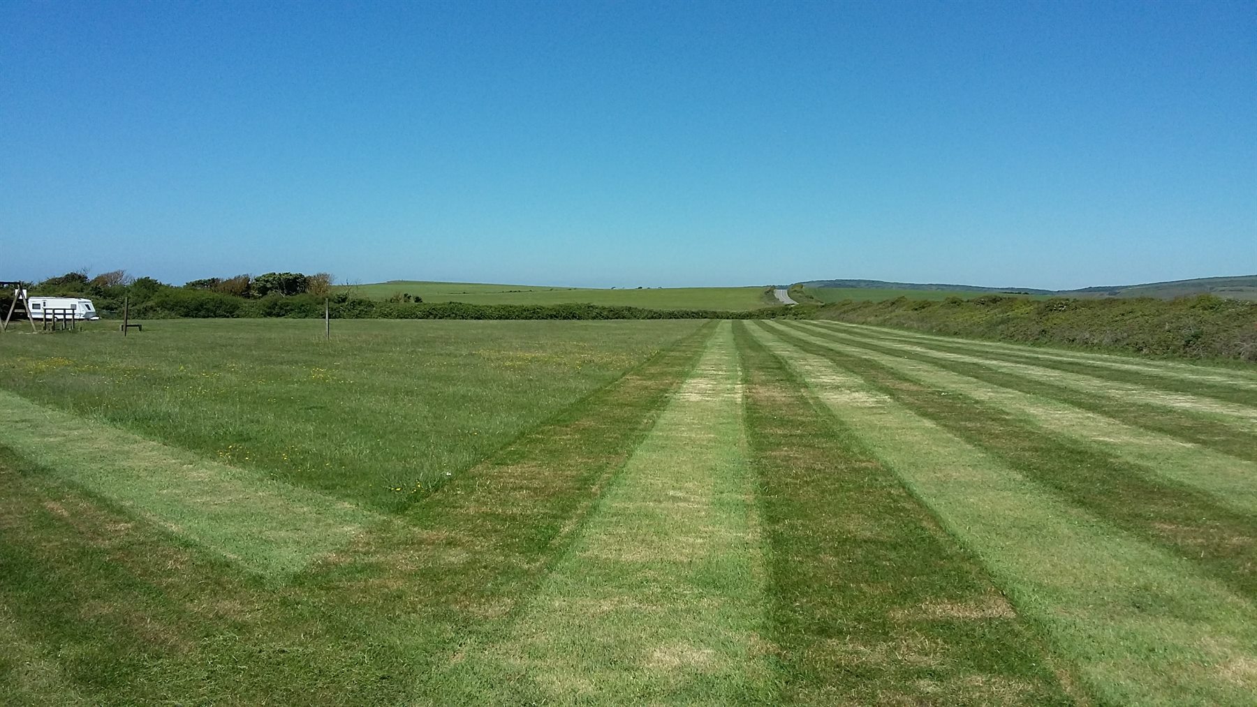 A broad green field with a freshly mown track