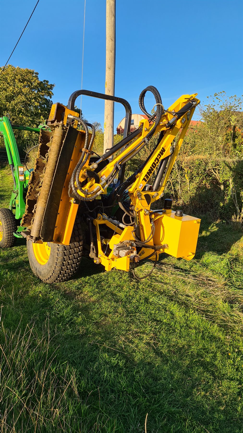 Tractor-mounted flail mower cutting back long grass and hedge growth