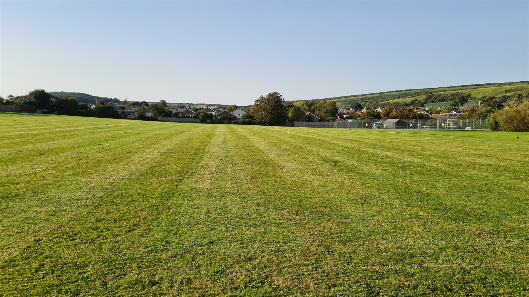 A large grassy field with freshly mown stripes