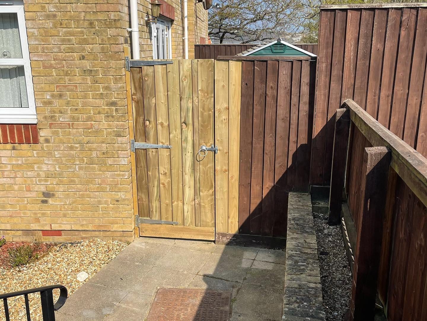 Timber garden gate beside a brick house