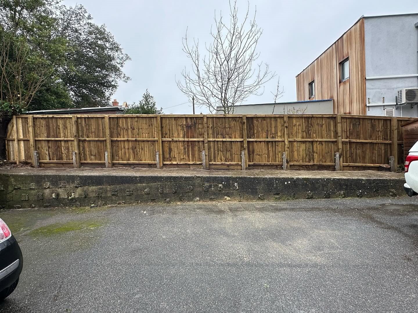 Timber boundary fence beside a paved driveway