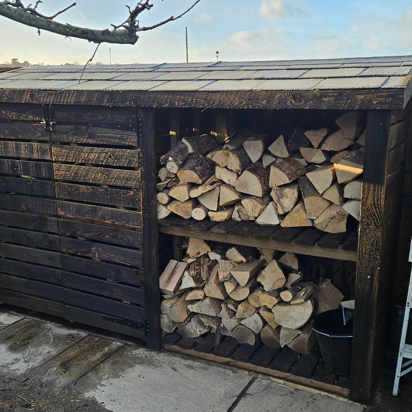 Timber garden shelter with a built-in log store