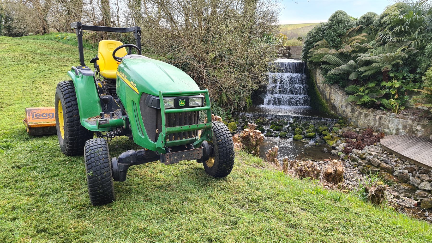 Compact tractor beside a landscaped water feature